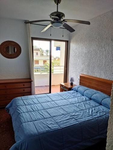 - une chambre avec un lit bleu et un ventilateur de plafond dans l'établissement ¡Piso familiar en Jávea!, à Jávea