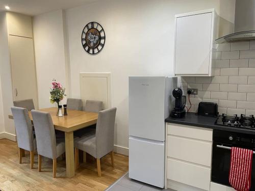 eine Küche mit einem Tisch mit Stühlen und einem Kühlschrank in der Unterkunft Home comfort 4 mins from Gatwick! in Horley