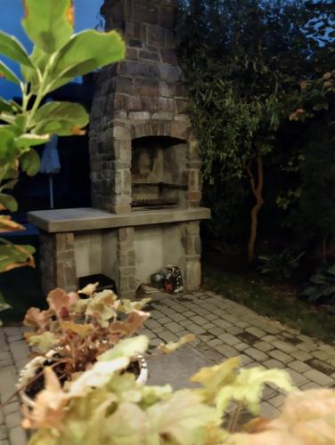 a brick fireplace in a garden with a cat laying on the ground at Barwny Zakątek in Augustów