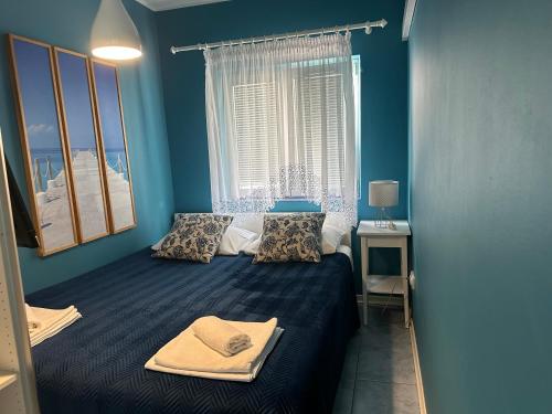 een slaapkamer met een bed met blauwe muren en een raam bij Adria Sun Apartments Vodice in Vodice