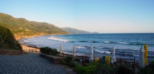 a sandy beach with waves in the ocean at Brancadoria B&B in Monteleone Rocca Doria