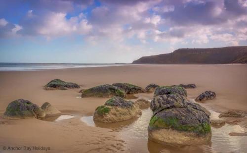 a beach with rocks in the sand and the ocean at Arthurs Escape in Filey