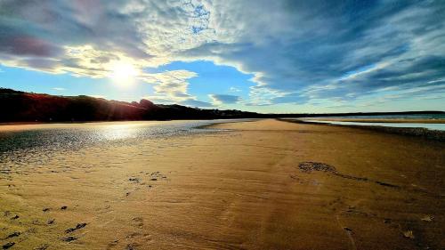 a beach with footprints in the sand under a cloudy sky at Arthurs Escape in Filey