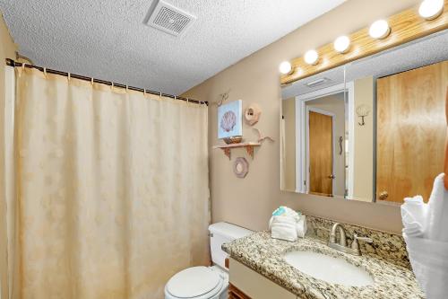 een badkamer met een wastafel, een toilet en een douchegordijn bij The Cove Unit 201A in Gulf Shores