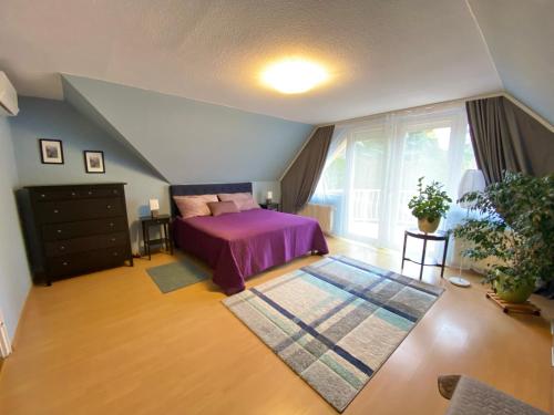 ein Schlafzimmer mit einem lila Bett und einem großen Fenster in der Unterkunft Teresa Guest House in Csömör
