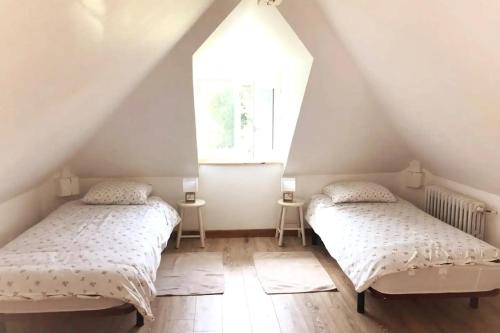 2 letti in una camera mansardata con finestra di Charmant cottage 8 personnes en Normandie a Cleuville