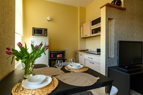 a kitchen with a table with two glasses and flowers at Center apartment Great Amber in Liepāja