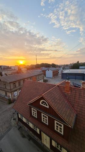 a view of a building with the sunset in the background at Center apartment Great Amber in Liepāja