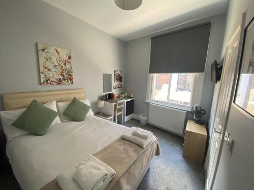 Grosvenor Place Guest House في تشيستر: غرفة نوم بسرير كبير ومخدات خضراء