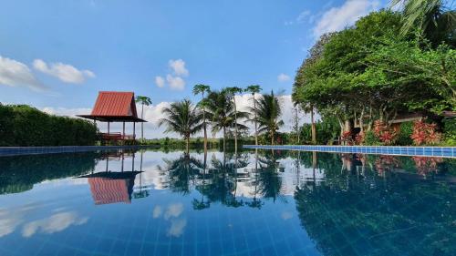 - une piscine bordée de palmiers et d'un kiosque dans l'établissement Tonkhao resort, à Ban Chuang
