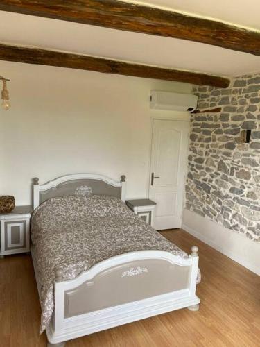 une chambre avec un lit et un mur en pierre dans l'établissement grande maison avec vue sur les Cevennes, à Canaules-et-Argentières