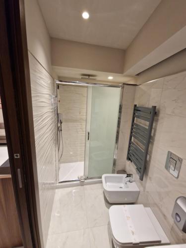 a bathroom with a shower and a toilet and a sink at Beatus Suites And Rooms B&B in Canicattì