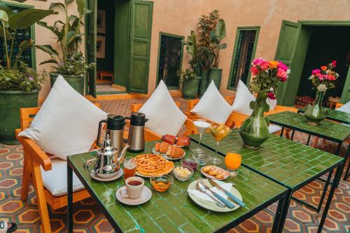 Hotel & Riad Veridis في مراكش: طاولة خضراء عليها طعام الإفطار