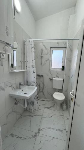 a white bathroom with a sink and a toilet at Sabo Villa in Pečurice