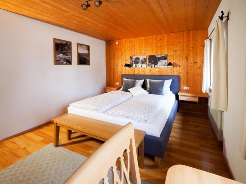 1 dormitorio con 1 cama y pared de madera en Beim Lenz, en Schleching