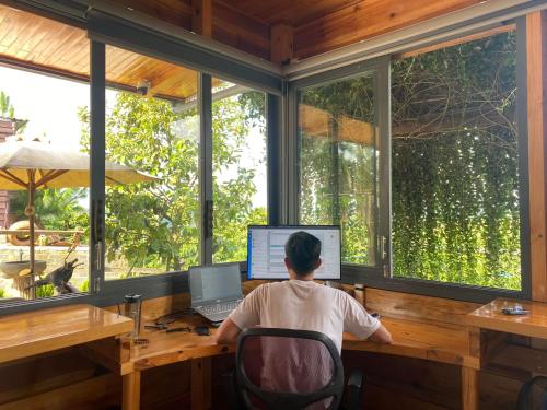 a man sitting at a desk in front of a computer at Lam Nguyên Charming House in Bao Loc