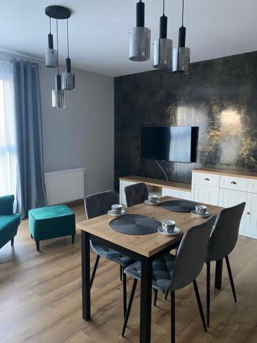 a dining room with a wooden table and chairs at Apartament Gdańsk Ujeścisko in Gdańsk