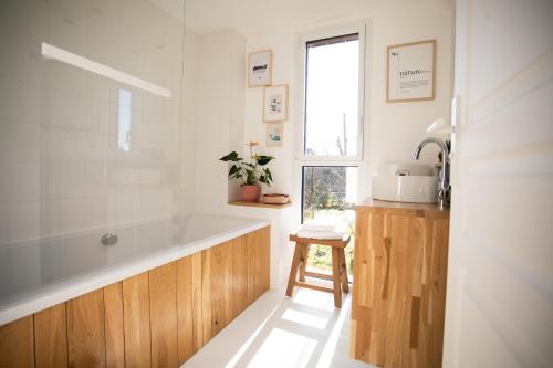 baño con bañera, lavabo y ventana en Aux Cabanes, en Grand-Laviers