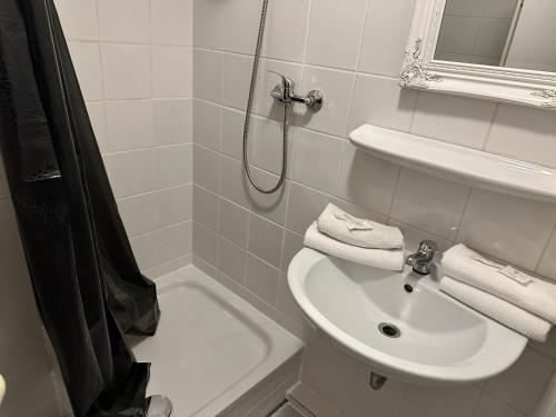 ein weißes Bad mit einem Waschbecken und einer Dusche in der Unterkunft Schokoladenmuseum - Top Lage - Souterrain Apartment in Köln