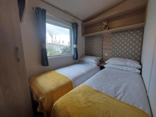 two beds in a small room with a window at Alphi 4 in Bude