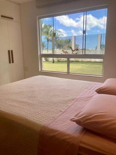 a bedroom with a bed and a large window at Beach Front Exclusive Villa with Pool in São Miguel do Gostoso