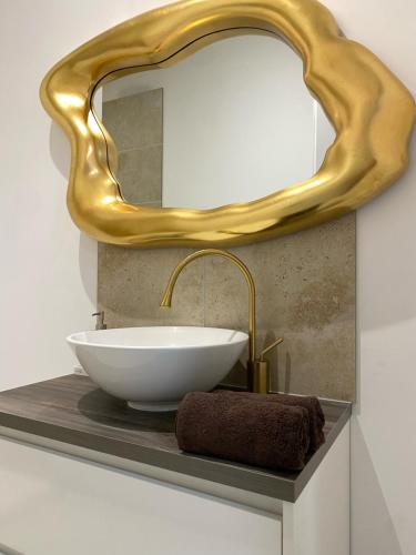 een badkamer met een wastafel en een gouden spiegel bij Logement dans propriété privée 2 in Saint Julien Les Rosiers