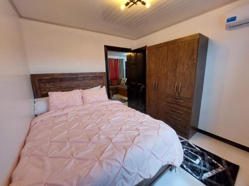 ein Schlafzimmer mit einem großen Bett und einem Holzschrank in der Unterkunft Cozy & Central 2 Bedroom Apt in Georgetown