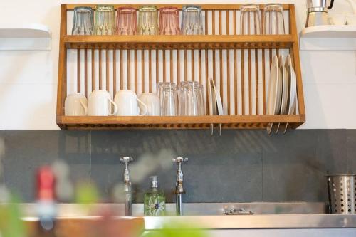 una encimera de cocina con fregadero y vasos en un estante en Janies Cottage~ Mousehole~Eclectic Interiors & Vintage Charm en Mousehole
