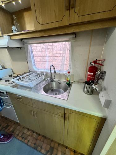 a small kitchen with a sink and a window at City Caravan, 5 mins from Cardiff city centre, Dog Friendly and perfect weekend Getaway in Cardiff