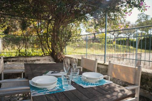 a wooden table with plates and glasses on top of it at Case Vacanze Ganimede in Sperlonga