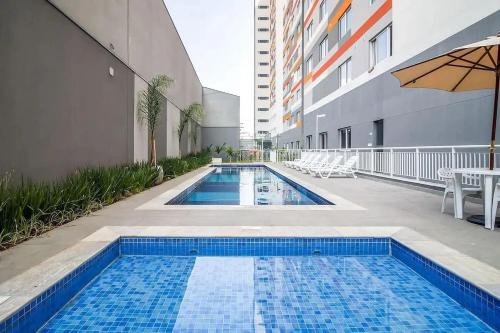 uma piscina ao lado de um edifício com um guarda-chuva em Completo, moderno e bem localizado na Rua do Metrô Brás SP em São Paulo