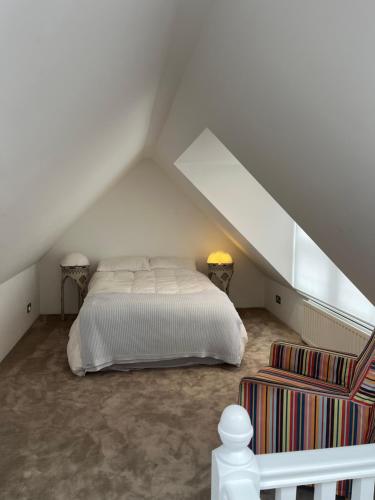 ein Schlafzimmer mit einem weißen Bett im Dachgeschoss in der Unterkunft The Loft in London