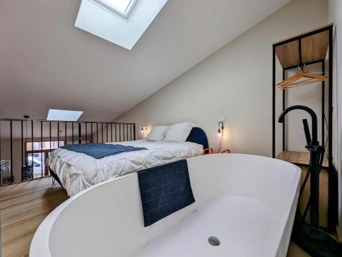 Schlafzimmer im Dachgeschoss mit einem Bett und einer Badewanne in der Unterkunft Loft d'Albenas - Clim et Bain in Loupian