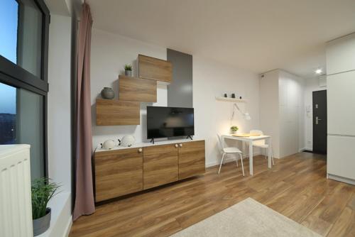 ein Wohnzimmer mit einem TV und einem Tisch mit einem Stuhl in der Unterkunft Apartament Wrocław in Breslau