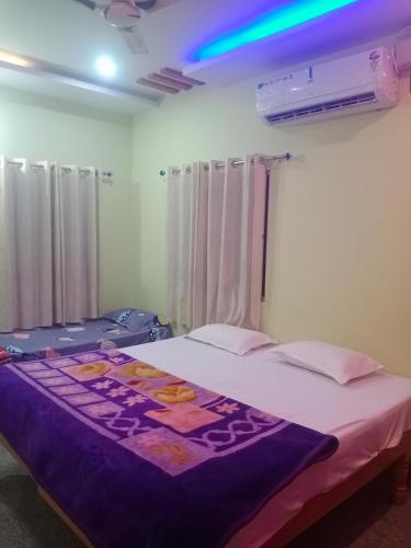 a bedroom with a bed with a purple blanket on it at Tharun home stay hampi in Hampi