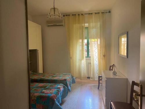 a room with two beds and a table and a mirror at Appartamento sul lungomare - Ladispoli in Ladispoli