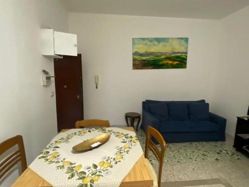 ein Wohnzimmer mit einem Tisch und einem blauen Sofa in der Unterkunft Appartamento sul lungomare - Ladispoli in Ladispoli