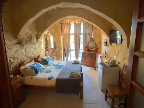- une chambre en pierre avec un grand lit dans l'établissement SUNRISE VIEW VILLA, à Qala