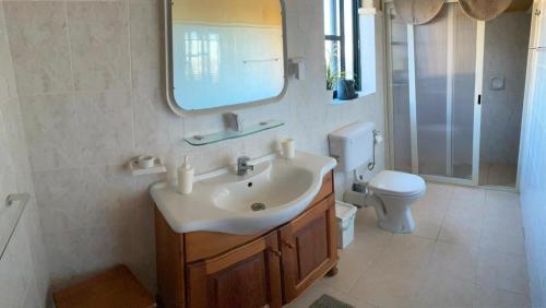 La salle de bains est pourvue d'un lavabo, de toilettes et d'un miroir. dans l'établissement SUNRISE VIEW VILLA, à Qala