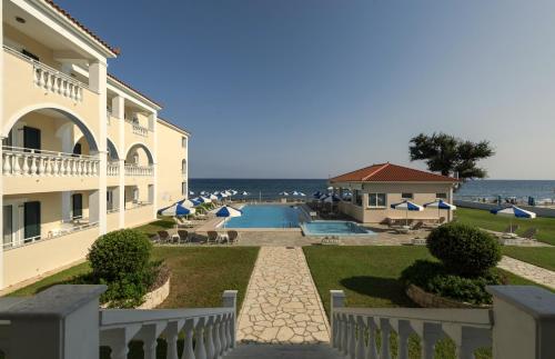 a building with a swimming pool next to the ocean at Maria Mare Apart-hotel in Argassi