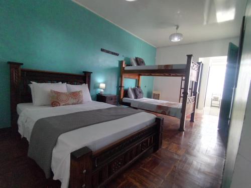 Lajuela BnB & Hostel في ألاخويلا: سريرين في غرفة نوم مع جدران خضراء