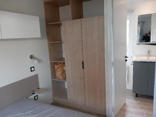 - une chambre avec une grande armoire en bois à côté d'un lit dans l'établissement MOBIL HOME CAMPING LES VIVIERS 4 ETOILEs, à Lège-Cap-Ferret