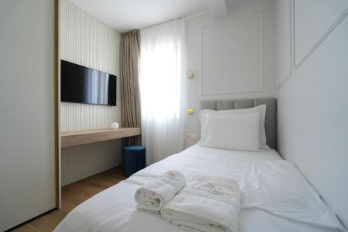 a bedroom with a white bed with towels on it at Adria Concept Suites in Zadar