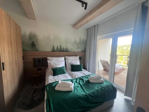Un dormitorio con una cama verde con toallas. en Apartament Hyrca en Szczyrk