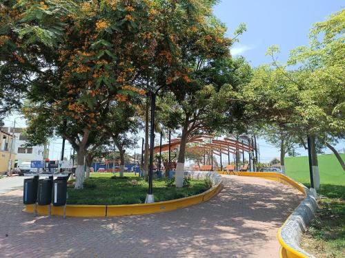 un parque con árboles y cubos de basura en una acera en Aristides Inn, en Huarmey