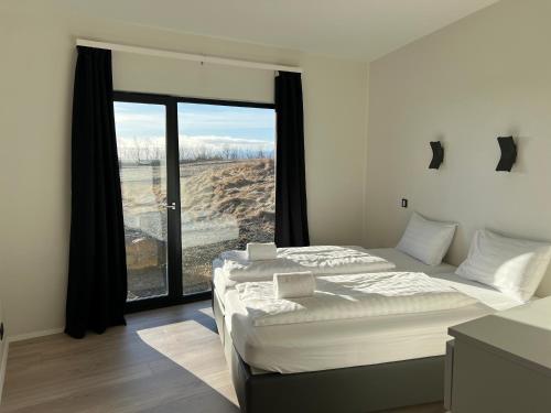 a bedroom with two beds and a large window at The Blackhouse in Höfn