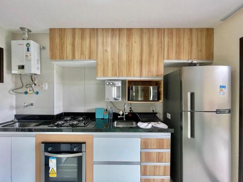 a kitchen with wooden cabinets and a stainless steel refrigerator at Resort VG SUN por Be My Guest! in Caucaia