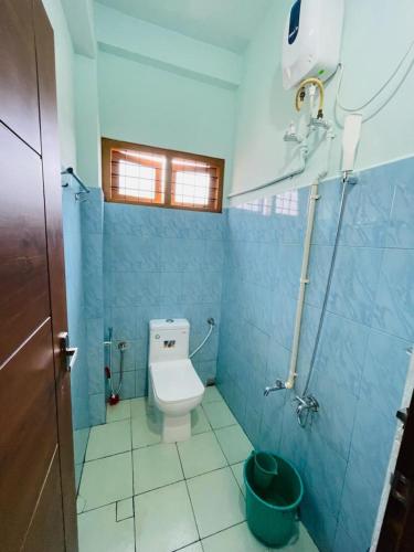 a bathroom with a toilet in a blue tiled room at FADHIYA RESIDENCY in Alwaye