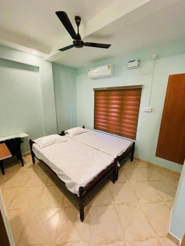 a bedroom with a bed with a ceiling fan at FADHIYA RESIDENCY in Alwaye