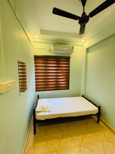 a room with a bed with a fan and a window at FADHIYA RESIDENCY in Alwaye